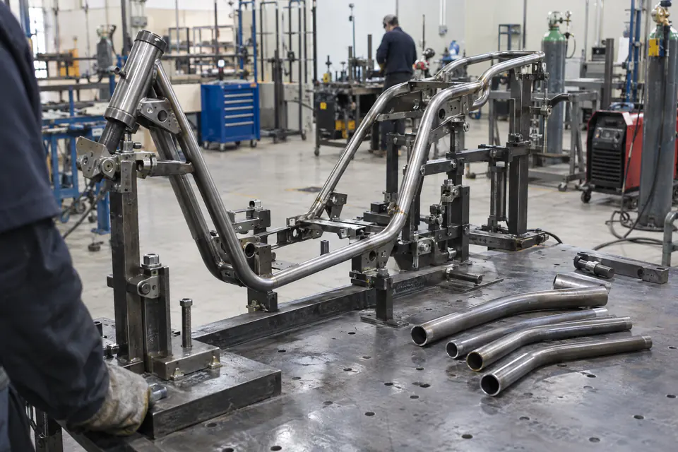 Illustration: a steel tube electric scooter chassis in a welding jig