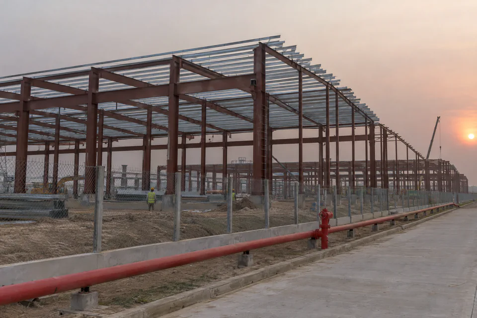 Illustration: a steel factory building frame and a red fire water main in an economic zone