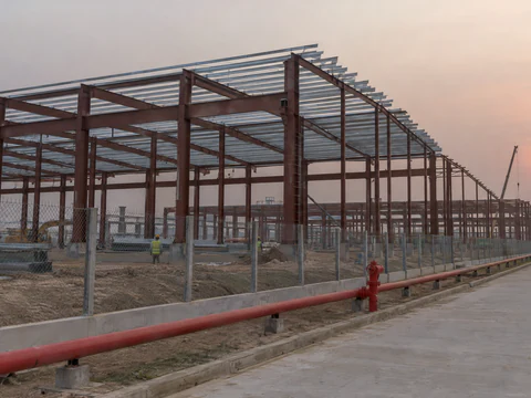 Illustration: a steel factory building frame and a red fire water main in an economic zone