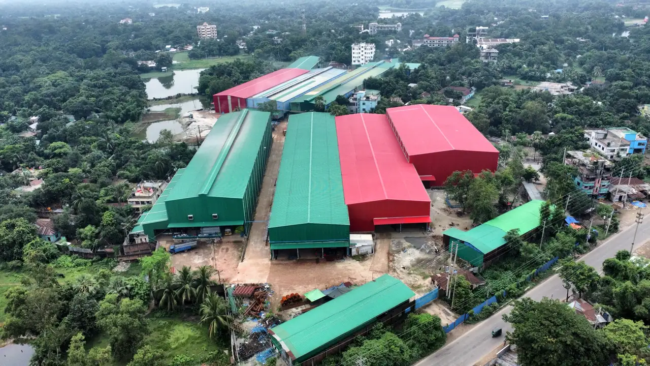 Aerial view of the Gram Bangla Tubes steel pipe plant in Sonargaon, with production sheds and pipe stock beside the road