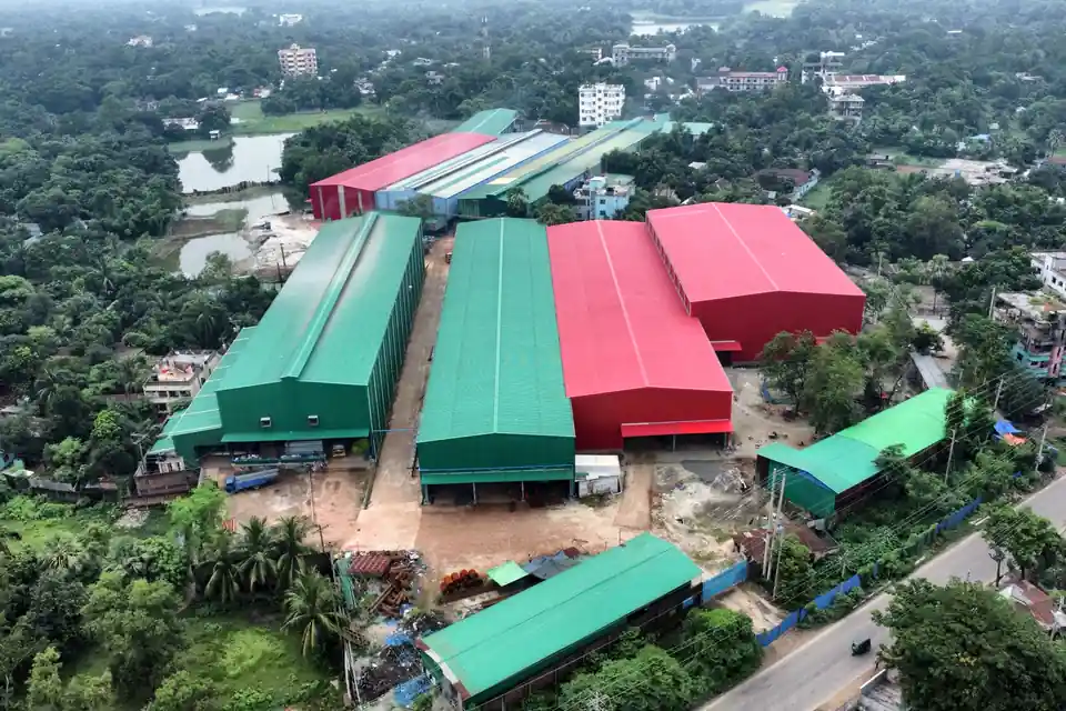 Aerial view of the Gram Bangla Tubes steel pipe plant in Sonargaon, with production sheds and pipe stock beside the road